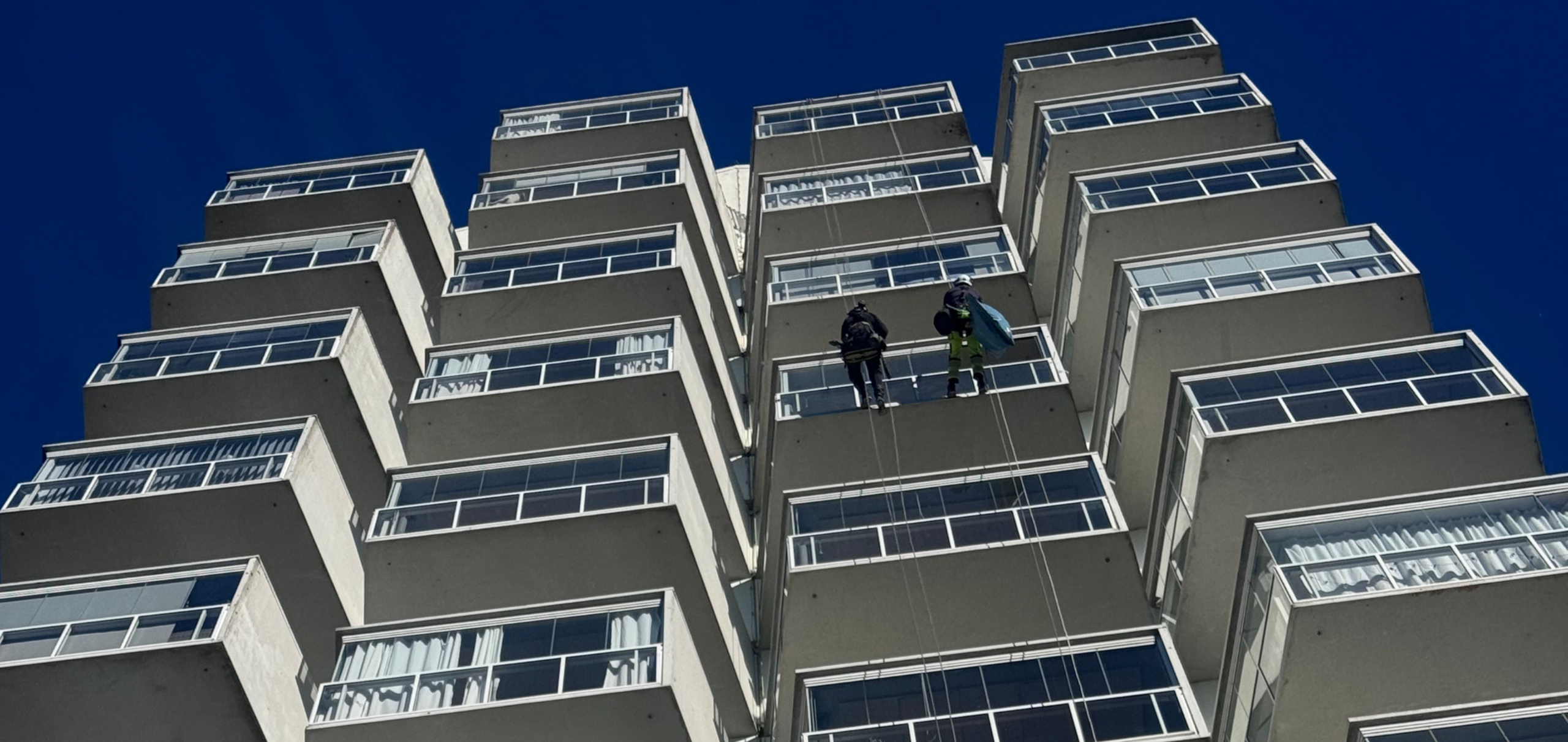 Två tekniker utför rope access-arbete på höghus fasad
